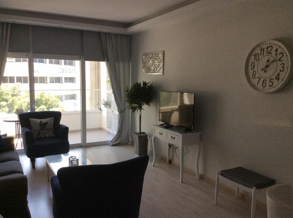 Armonia Suite lounge with TV, large wall clock and balcony view in central Nicosia Cyprus