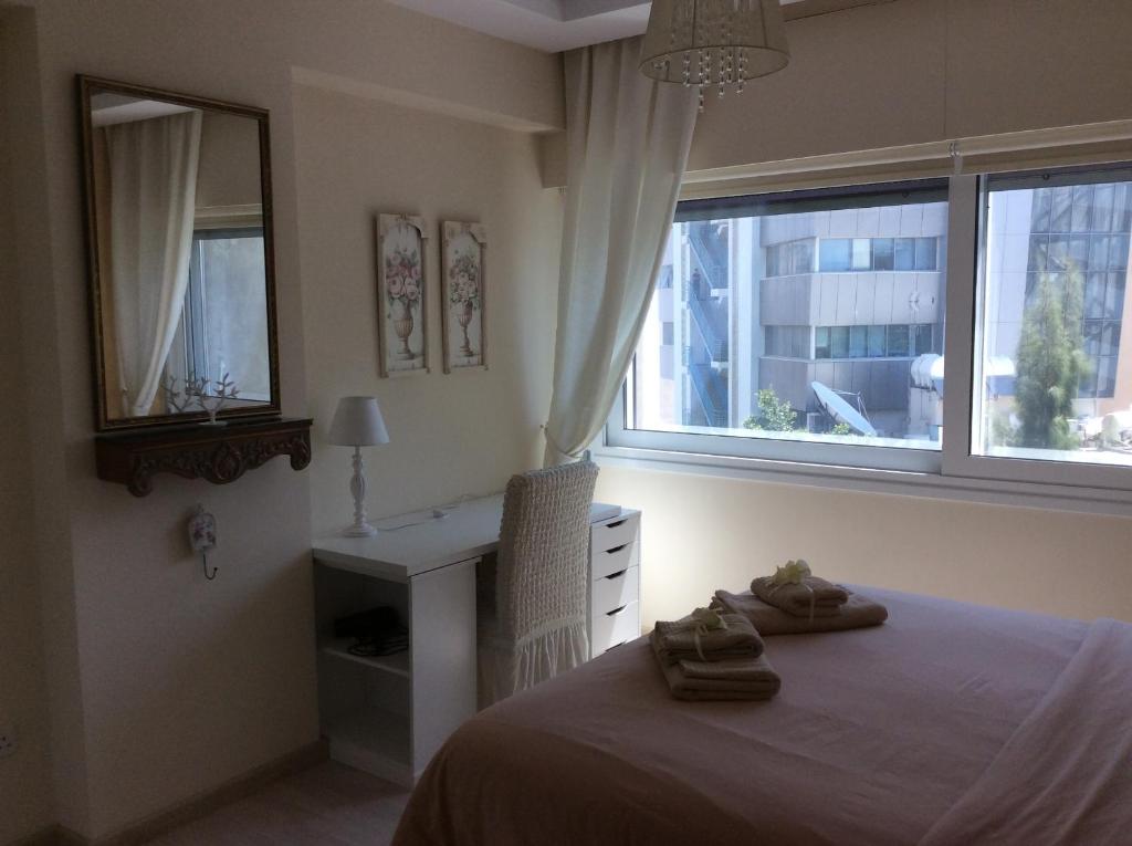 Fantasia Suite bedroom with mirror, desk and large city window in central Nicosia apartment