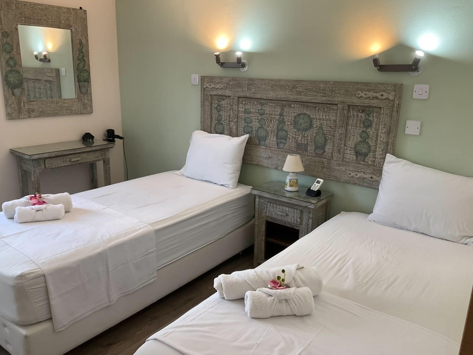 Twin bedroom with sage green walls and carved wooden headboard at the Vintage Suite in central Nicosia