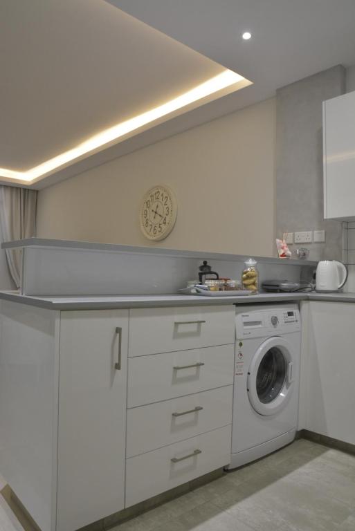 Kitchen utility area with washing machine and decorative wall clock at the Armonia Suite Nicosia