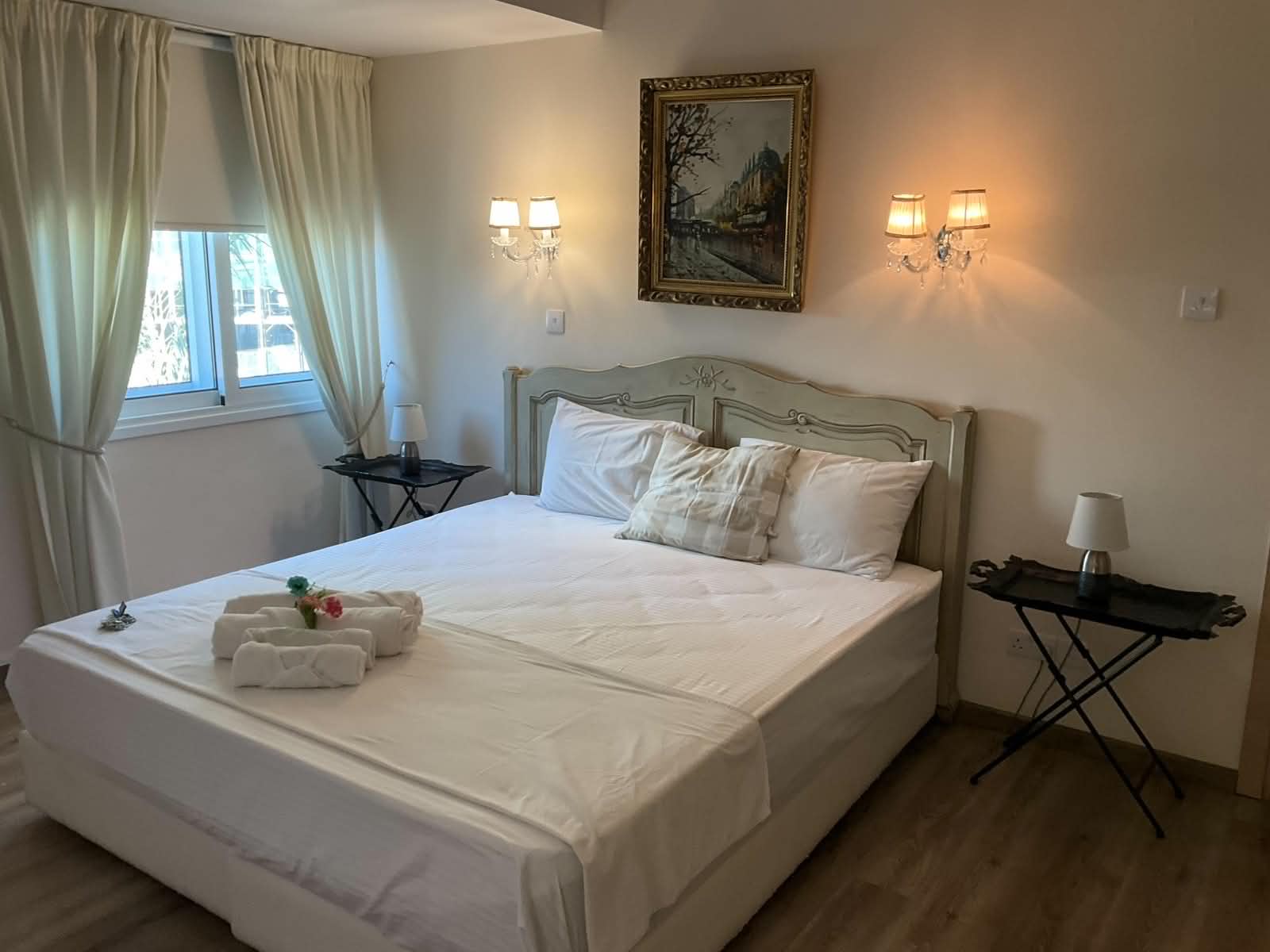 Vintage Suite master bedroom with double bed, carved headboard and framed Paris cityscape art in central Nicosia
